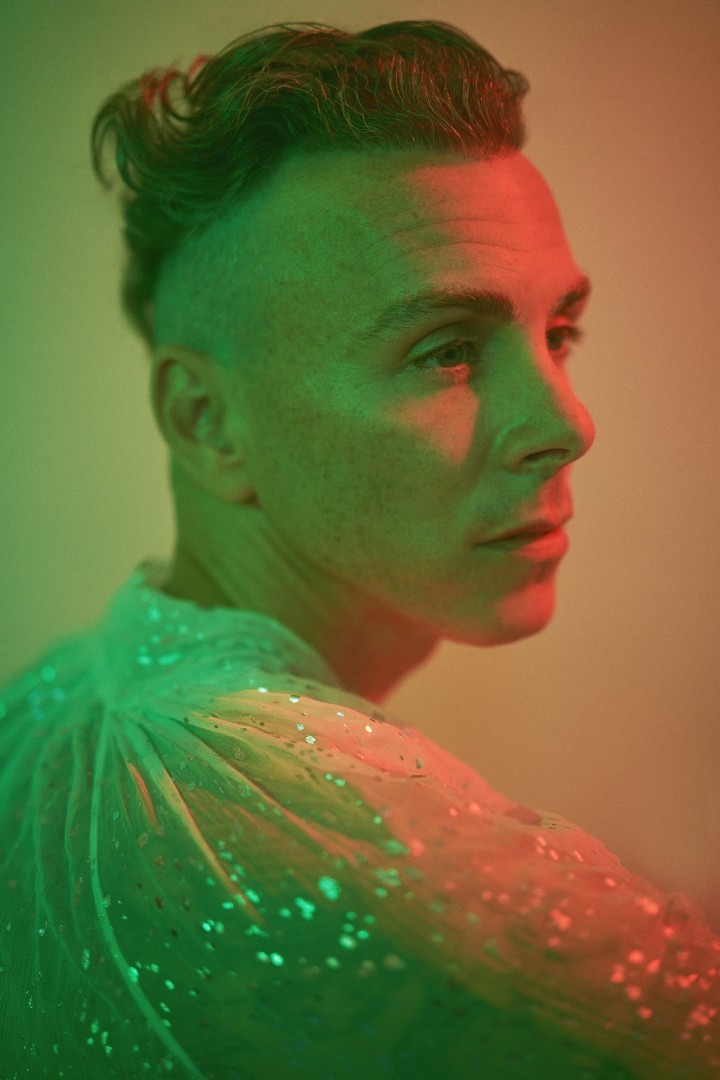 Der Sänger Asaf Avidan im Profil mit einem glitzernden Hemd und in grün-roter Beleuchtung