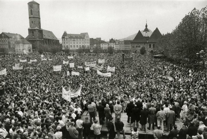Demonstranten auf dem Eichplatz im Herbst 1989 in Jena, im Hintergrund Stadtkirche und Rathaus