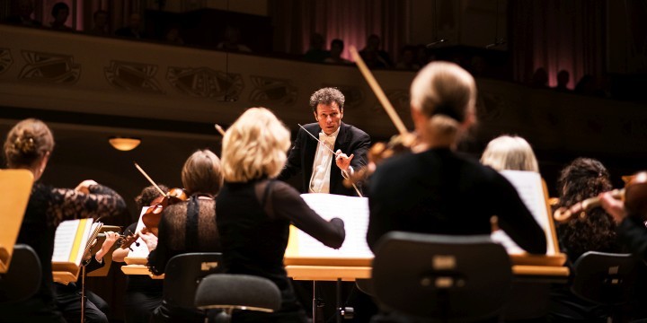 Dirigent und GMD Simon Gaudenz im Volkshaus Jena mit Musiker:innen Jenaer Philharmonie im Vordergrund