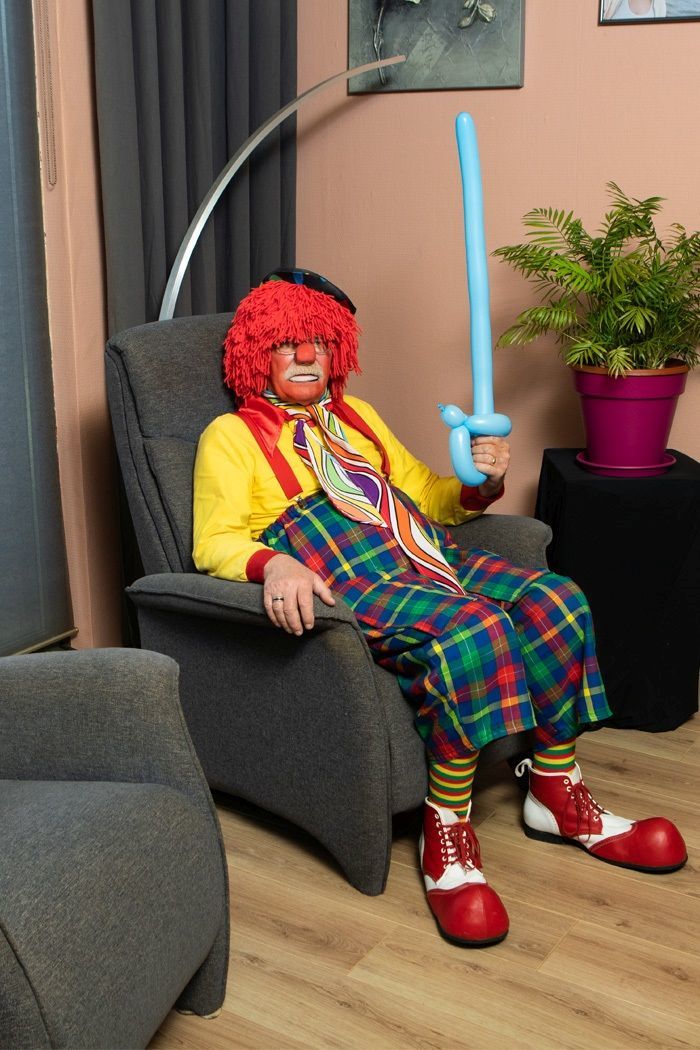 Clown in einem Sessel mit Luftballon