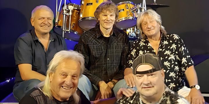 Die 5-köpfige Band sitzt vor einem Schlagzeug