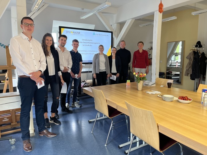 Gruppe von Menschen in einem Konferenzraum vor einer Bildschirmpräsentation von JenaKultur und Ernst-Abbe-Hochschule Jena