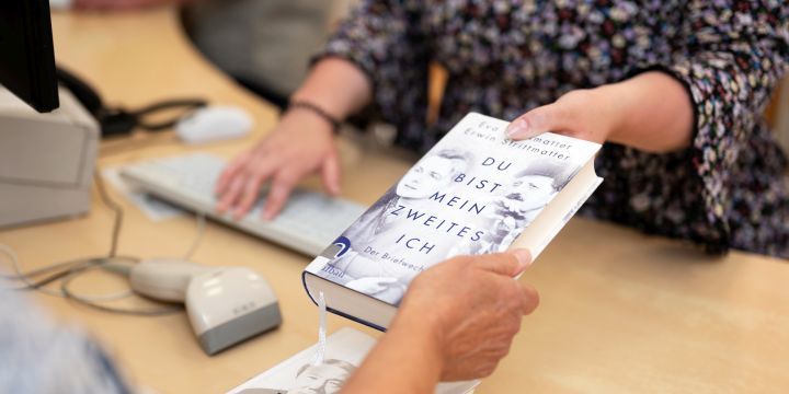 An der Ausleihe der Ernst-Abbe-Bücherei Jena übergibt eine Mitarbeiterin ein Buch an den Kunden