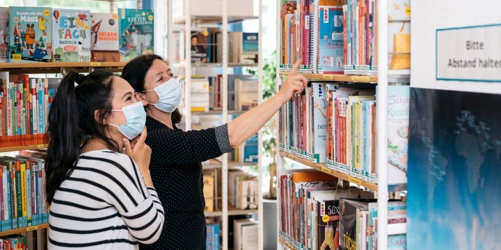 Mitarbeiterin und Besucherin in der Ernst-Abbe-Bücherei Jena-Lobeda mit Corona-Masken vor einem Bücherregal  ©JenaKultur, C. Worsch