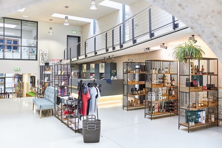 Blick in den Shop der Jena Tourist-Information mit Tresen, Sitzgelegenheiten, Regalen und Garderobenständern mit lokalen Produkten