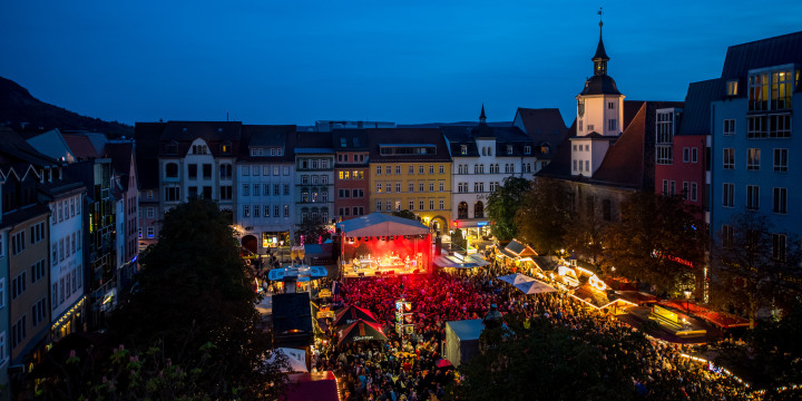Blick auf den Marktplatz Jena beim Altstadtfest mit erleuchteter Bühne, Ständen und Publikum