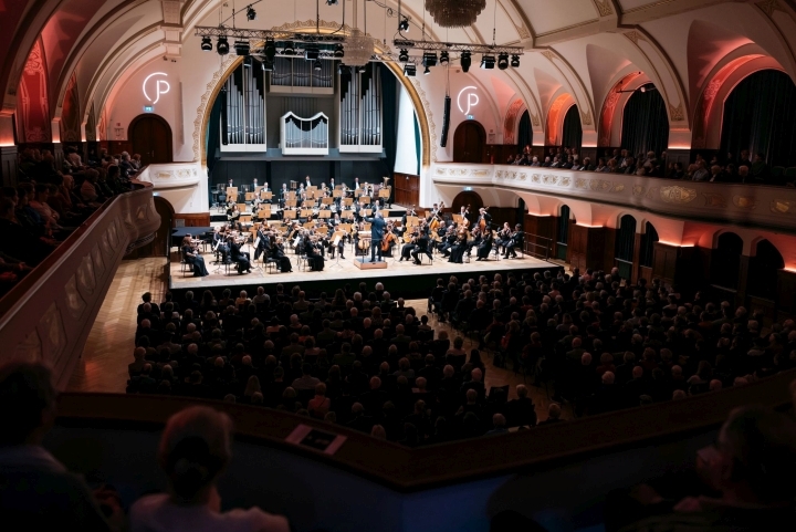 Bild vom Rang des Volkshauses Jena durch das Publikum: Das Orchester der Jenaer Philharmonie spielt auf der Bühne