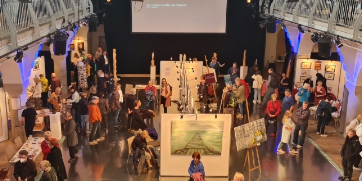 Ein Blick auf den Kunstmarkt Jena von der Empore des Volksbads Jena mit Aussteller:innen und Gästen