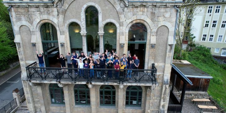 Der Knabenchor der Jenaer Philharmonie steht auf dem Balkon des Normannenhauses und winkt in die Kamera der Drohne