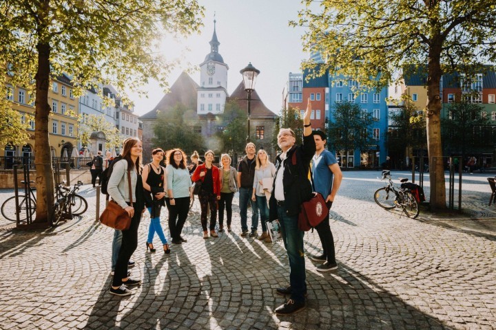 Gruppe einer Stadtführung auf dem Jenaer Marktplatz vor dem Hitsorischen Rathaus