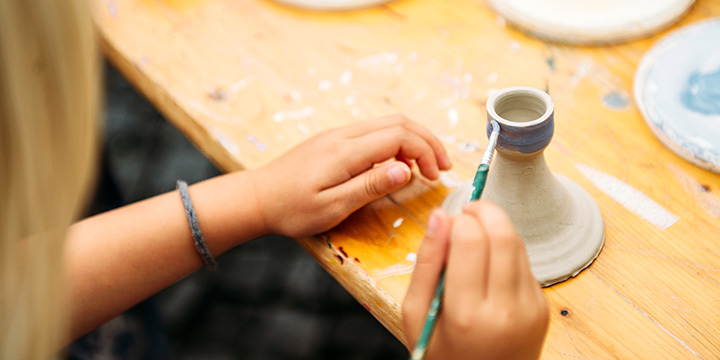 EIne Kinderhand bemalt ein kleines Tonobjekt