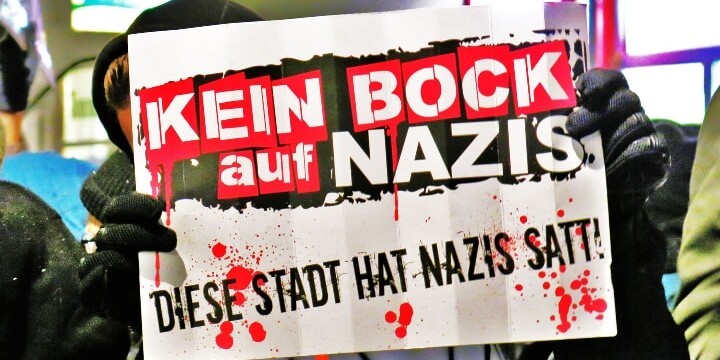 Person hält Schild vors Gesicht, auf dem steht "Kein Bock auf Nazis. Diese Stadt hat Nazis satt!"