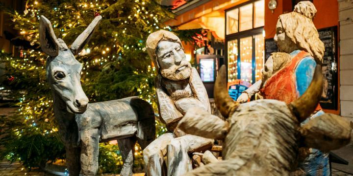 Blicka uf die abendliche Weihnachtskrippe Jena, einige der vielen Figuren, im Hintergrund der beleuchtete Weihnachtsbaum