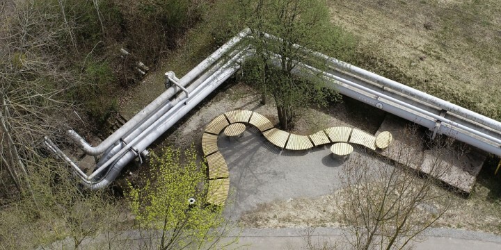 Bank, die sich in Bogen vor Fernwärmeleitungen im Jenaer Paradiespark schlängelt