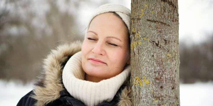 Frau lehnend an Baum im Winter mit Schal und Haarband