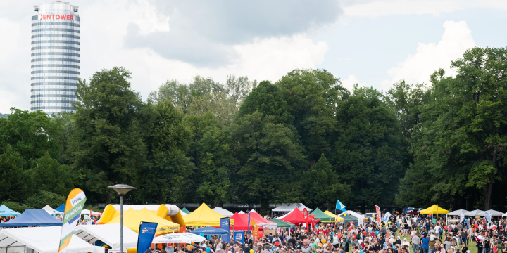 Stände, buntes Gewimmel von Gästen in einem grünen Park und der Jentower im Hintergrund.  ©JenaKultur, C. Worsch