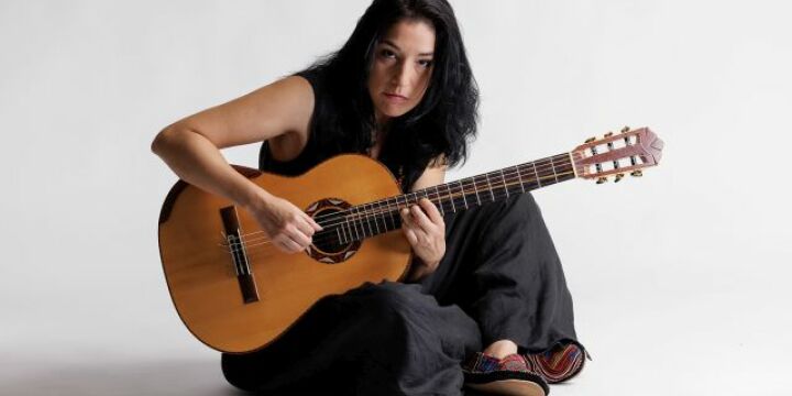 Frau mit Gitarre sitzt auf dem Boden