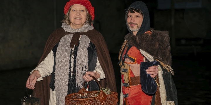 Eine Dame als Kräuterweib und ein Herr als mittelalterlicher Scharfrichter verkleidet ziehen im Dunkeln durch Jena