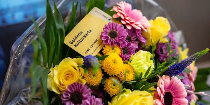 Ein Blumenstrauße, in dem die Goldene Kulturkarte der Stadt Jena steckt  &copy;JenaKultur, C. Worsch