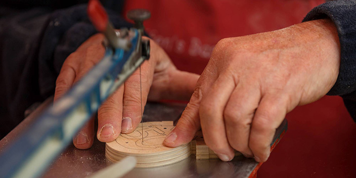 Zwei Hände bewegen ein kleines Stück Holz durch eine Stichsäge  ©JenaKultur, A. Beetz | studiobeetz.de