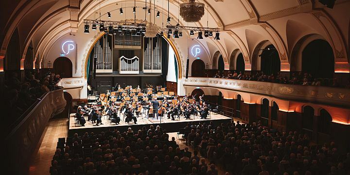 Jenaer Philharmonie, Blick in das Volkshaus Jena mit der Bühne, den Musiker:innen und Publikum  ©JenaKultur, C. Worsch