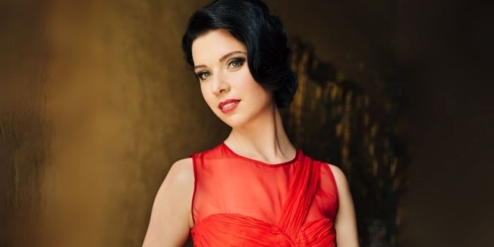 Margarita Vilsone posiert in einem roten Ballkleid vor einem braunen Hintergrund