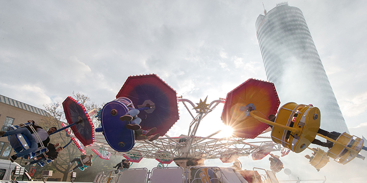 Breakdanceartiges Rummelfahrgeschäft, dessen Gondeln in der Luft sind und sich vor dem Jentower auf den Jenaer Frühlingsmarkt bewegen.  ©JenaKultur, R. Möbius