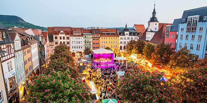 Bei Dämmerung Aufnahme des Marktplatzes während des Jenaer Frühlingsmarktes aus der Vogelperspektive mit beleuchteter Bühne und vielen Menschen.  ©JenaKultur, C. Worsch