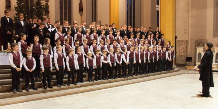 Der Knabenchor Jena singt mit Dirigentin in der Schillerkirche. Die jüngeren Kinder tragen Anzüge mit roter Weste, die Älteren tragen schwarze Anzüge