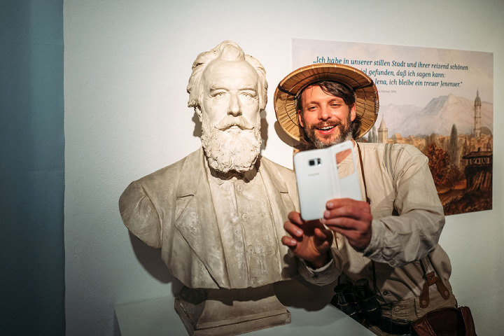 Mann mit Tropenhut macht ein Selfie mit der Büste von Ernst Haeckel