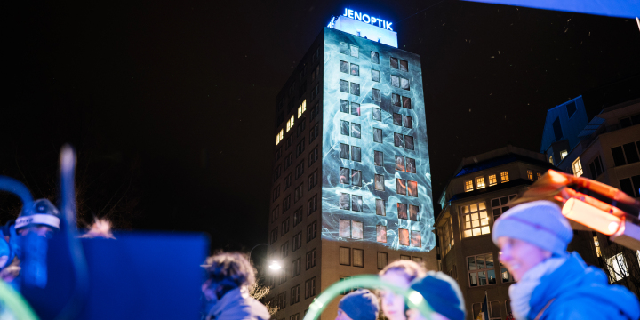 Beleuchter Turm von Jenoptik, davor bewegen sich Leute  &copy;JenaKultur, C. Worsch