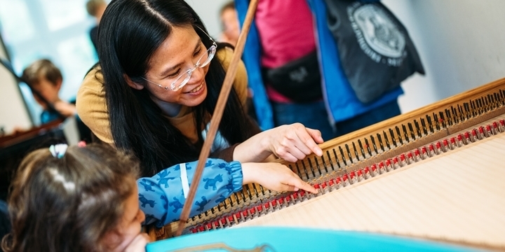 Beim Tag der offenen Tür an der MKS Jena zupft ein Kind die Saiten in einem Flügel an