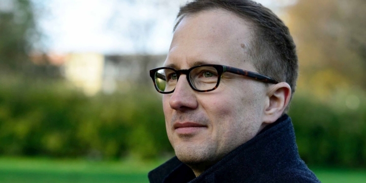 Nahaufnahme freundlich lächelnder Mann mit Brille und aufgestelltem Mantelkragen  ©Ulrike von Loeper