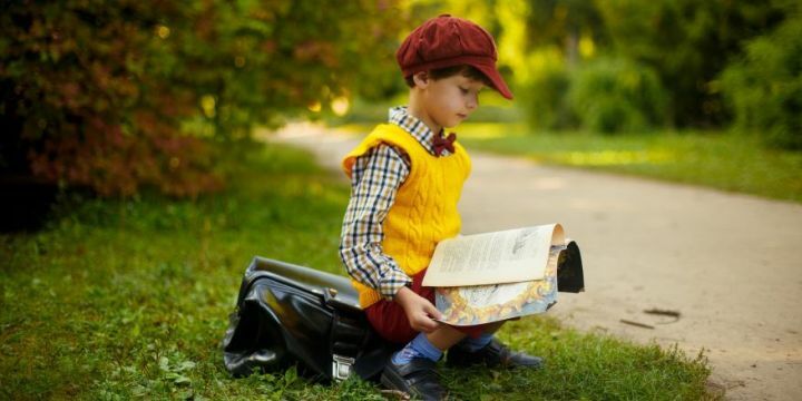 Junge mit Baskenmütze liest in einem Buch