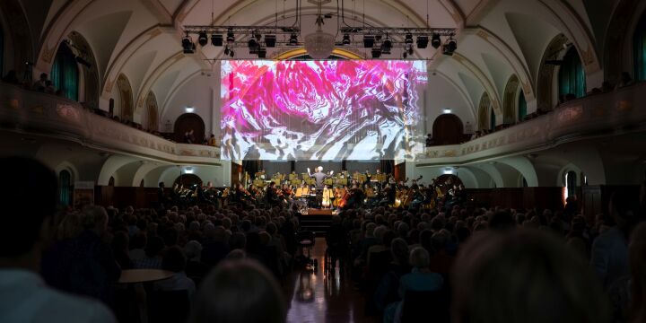 Blick zur Bühne im Volkshaus mit Orchester und Lichtkunst im Hintergrund  &copy;JenaKultur, C. Worsch