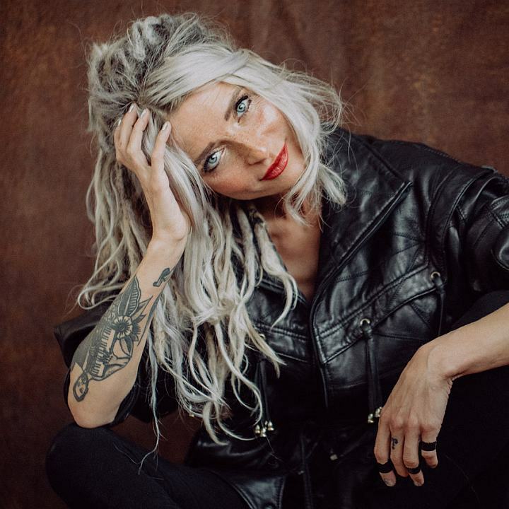 Sarah Lesch Postrait, die sitzt auf dem Boden und lächelt, blonde lange Haare