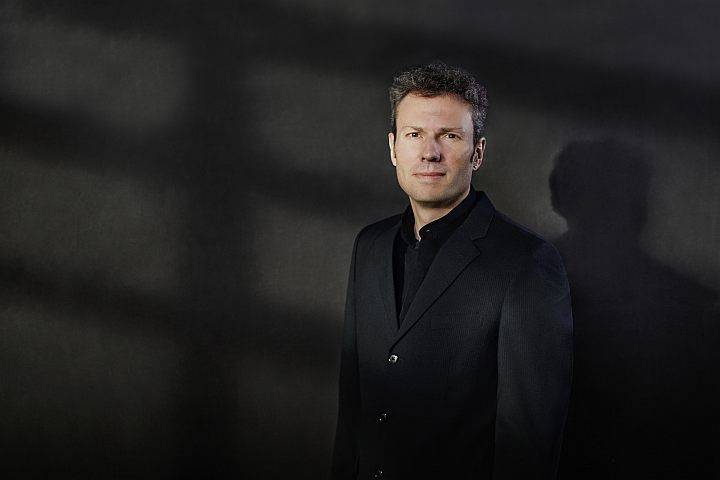 Simon Gaudenz im schwarzen Anzug vor schwarzem Hintergrund