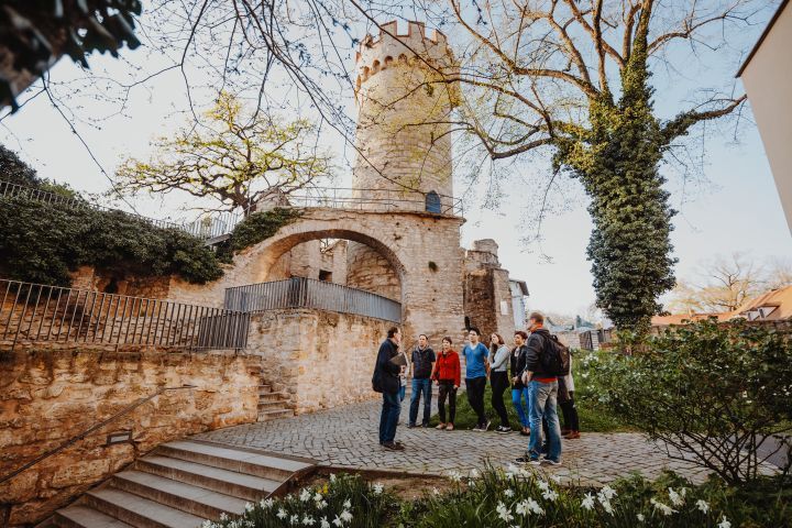 Eine Stadtführungsgruppe steht vor dem historischen Stadtmauerensemble in Jena