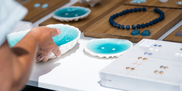 Eine Hand untersucht die kunstvollen Schalen in Form einer Muschel, daneben liegt Schmuck aus Ton.  ©JenaKultur, C. Worsch