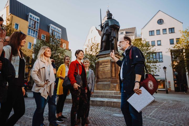 Gruppe von Menschen mitten auf dem Jenaer Marktplatz, vor dem Hanfried bei einer Stadtführung