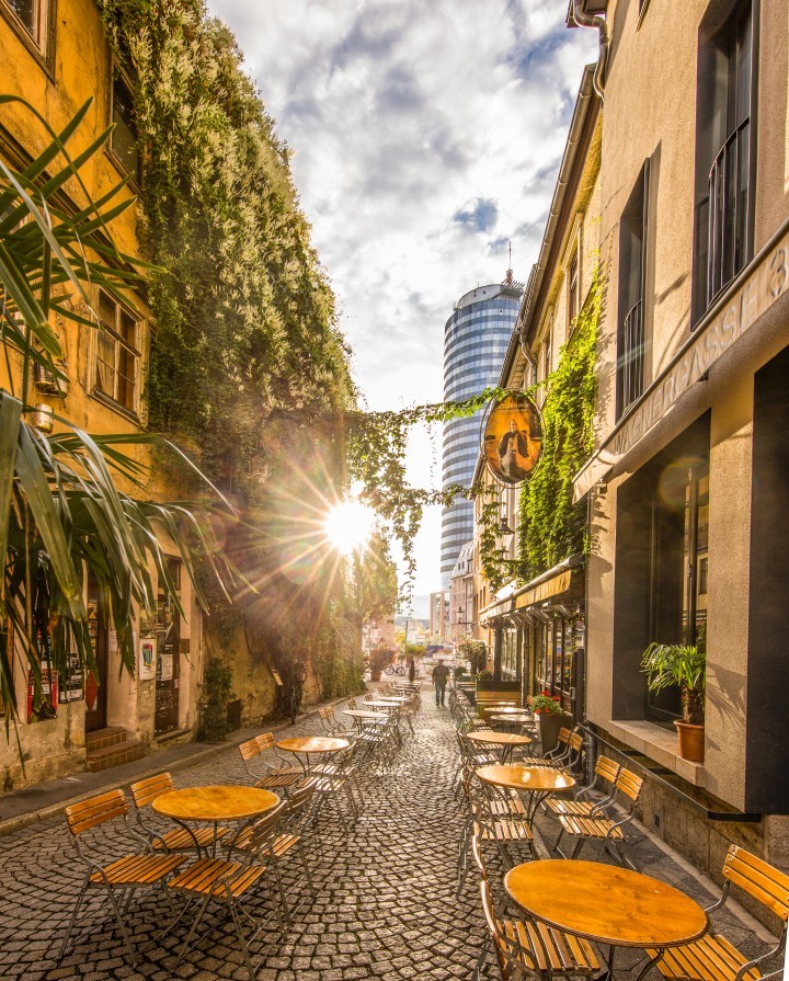 Café-Bestuhlung in der Jenaer Wagnergasse mit Sonnenaufgang hinter dem JenTower